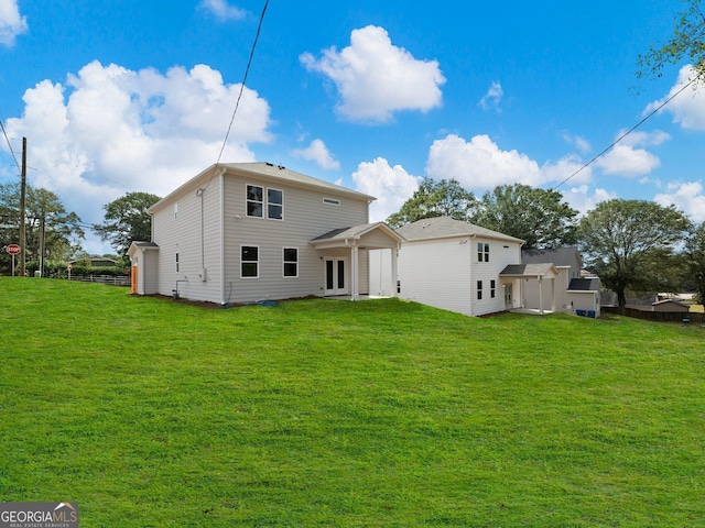 rear view of house featuring a yard and fence