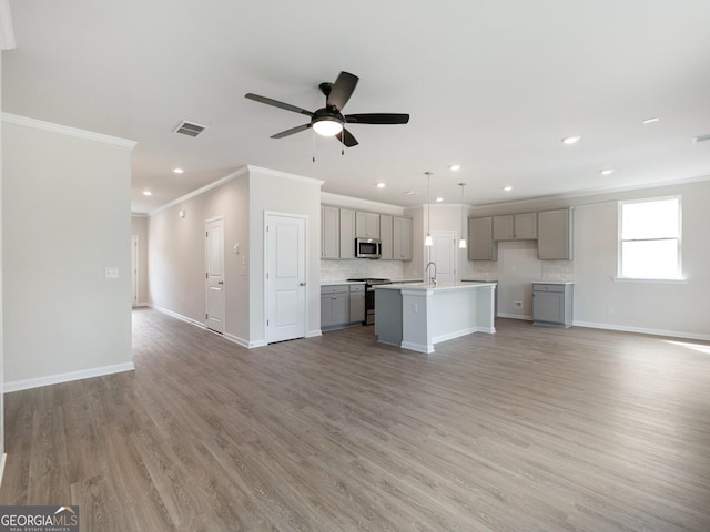 unfurnished living room featuring visible vents, crown molding, light wood-style flooring, and baseboards