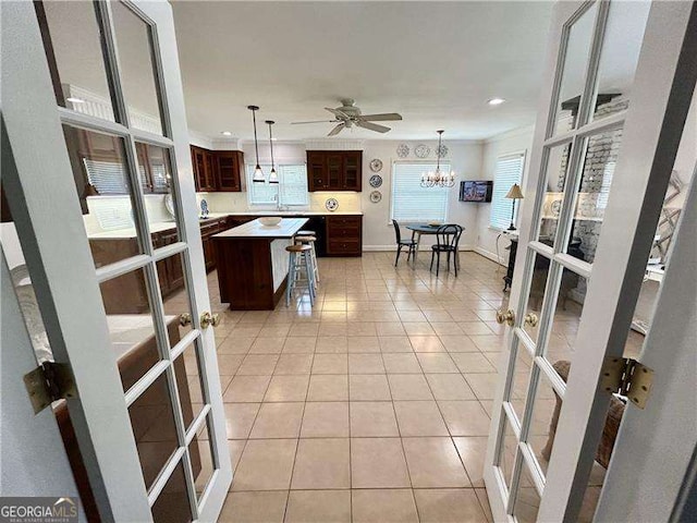 kitchen featuring light tile patterned floors, a kitchen island, a breakfast bar area, ceiling fan, and dark brown cabinets