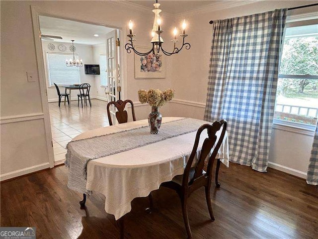 dining space with dark hardwood / wood-style floors, an inviting chandelier, crown molding, and plenty of natural light