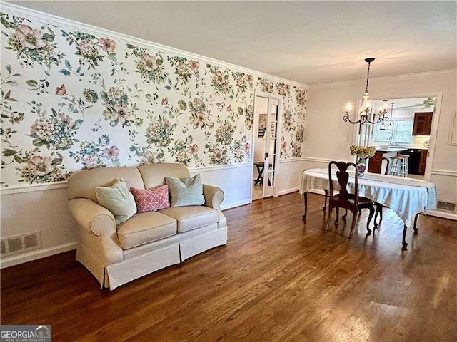 living room featuring a chandelier, crown molding, and dark wood-type flooring