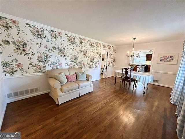 living room with a notable chandelier, crown molding, and dark wood-type flooring