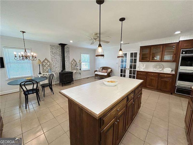 kitchen featuring a kitchen island, stainless steel double oven, a wood stove, and light tile patterned floors