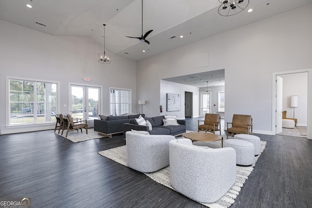 living room featuring a towering ceiling, dark wood-type flooring, french doors, and ceiling fan with notable chandelier