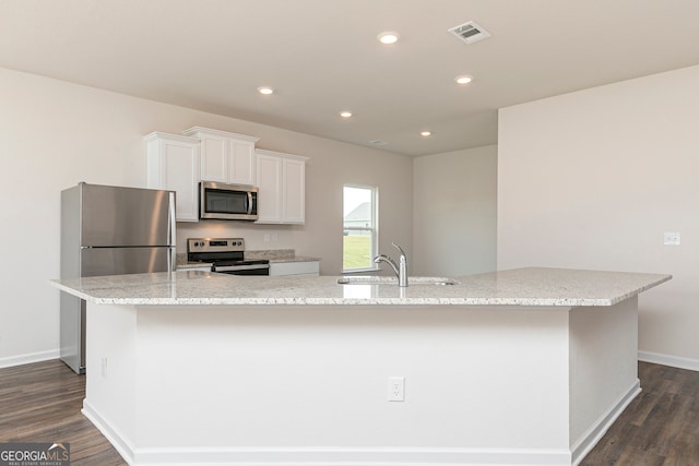 kitchen with stainless steel appliances, white cabinetry, and a large island with sink