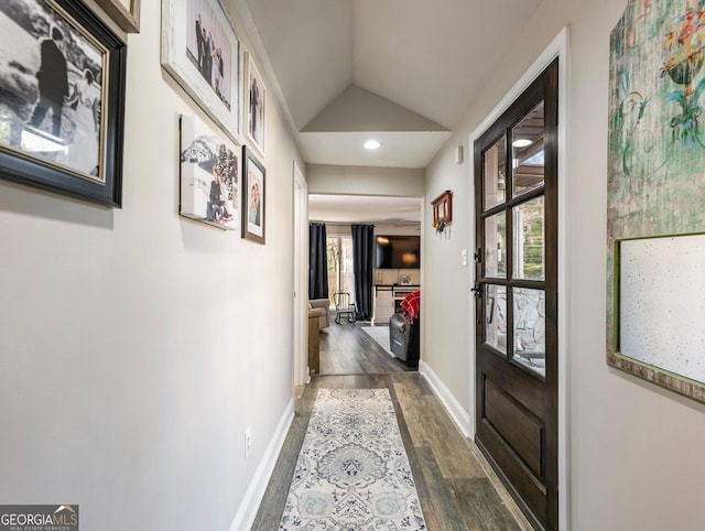 corridor featuring dark wood-type flooring, plenty of natural light, and vaulted ceiling