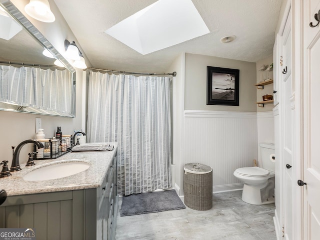 bathroom featuring vanity, toilet, a skylight, and a textured ceiling