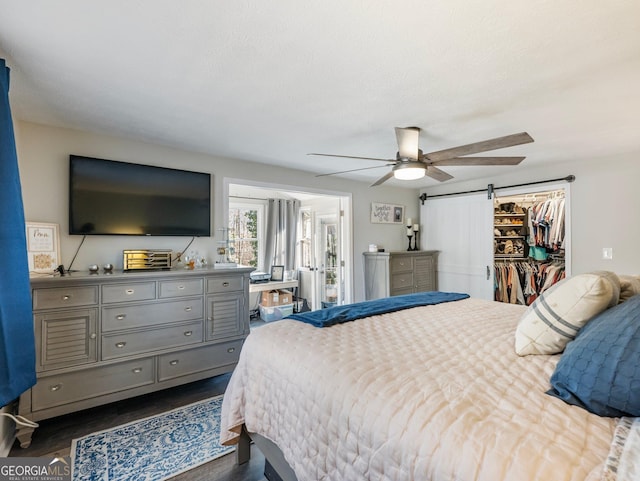 bedroom with a closet, a spacious closet, a barn door, and ceiling fan