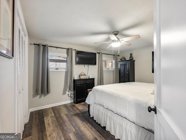 bedroom with dark wood-type flooring, ceiling fan, a closet, and multiple windows