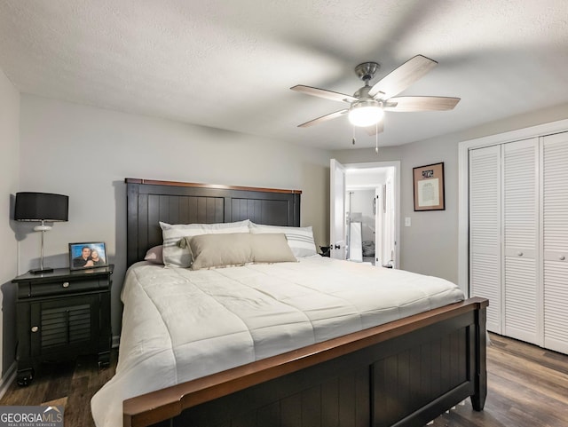 bedroom featuring dark wood-type flooring, ceiling fan, a closet, and a textured ceiling