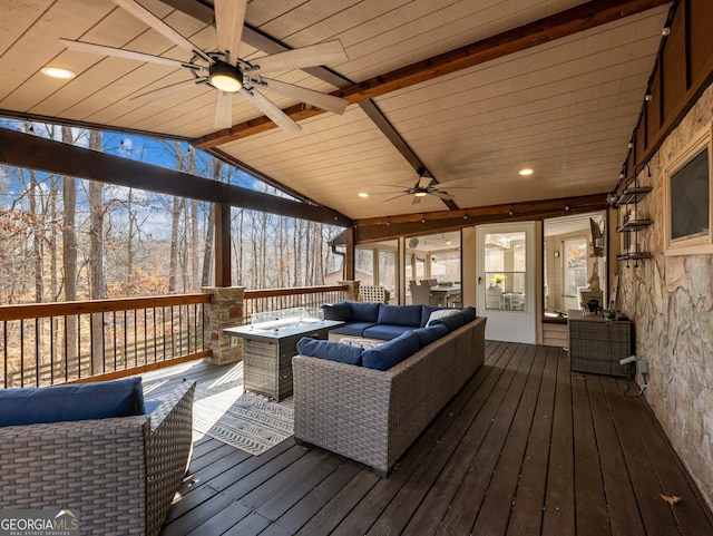 wooden terrace featuring ceiling fan and an outdoor living space with a fire pit