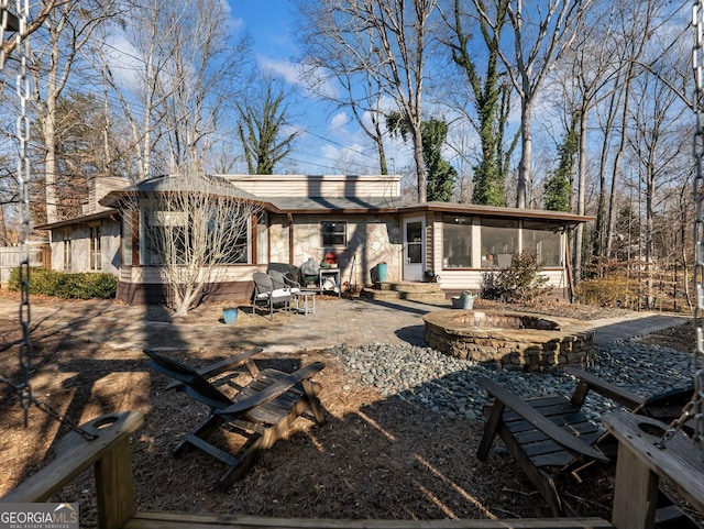 back of house featuring a sunroom, a fire pit, and a patio