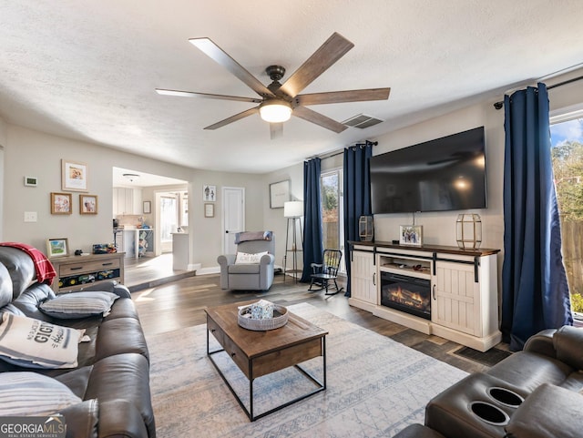 living room with ceiling fan, wood-type flooring, and a textured ceiling