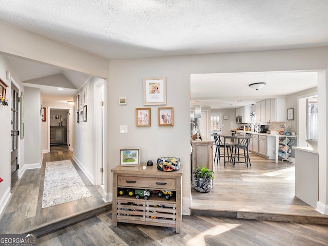 hall featuring sink, hardwood / wood-style floors, and a textured ceiling