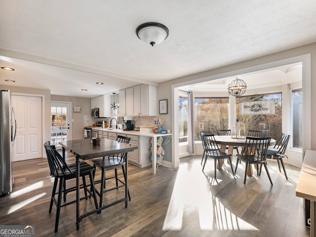 dining space featuring sink, a healthy amount of sunlight, dark wood-type flooring, and a textured ceiling