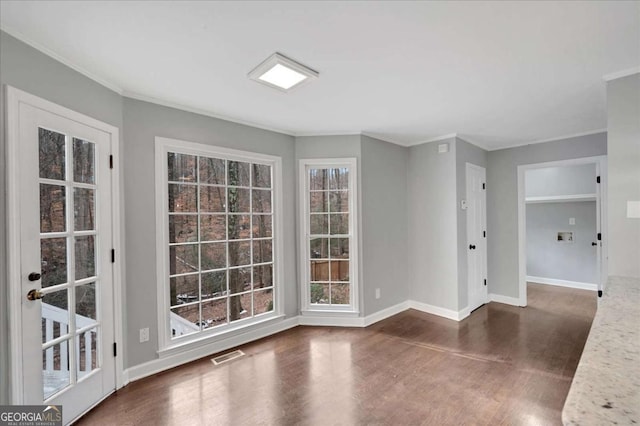 empty room with a wealth of natural light, dark hardwood / wood-style flooring, and crown molding