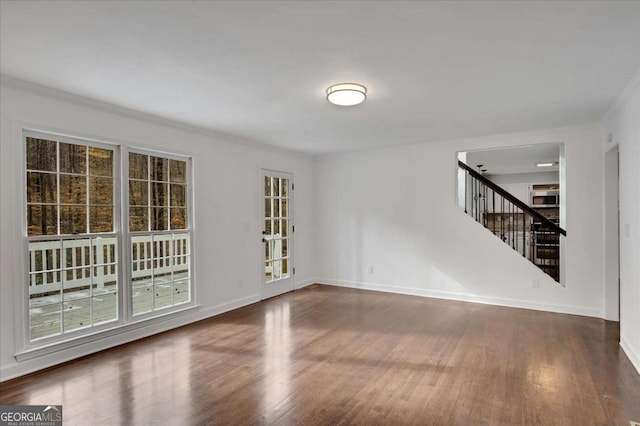 empty room with ornamental molding and dark hardwood / wood-style flooring