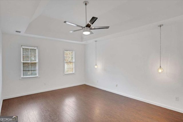 unfurnished room featuring ceiling fan, a tray ceiling, and dark wood-type flooring