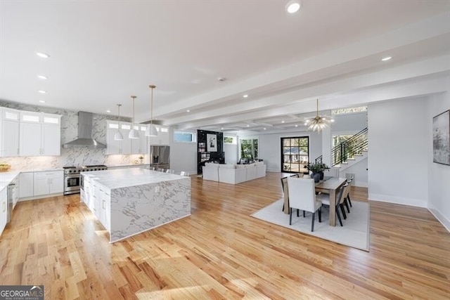 kitchen with decorative light fixtures, a center island, white cabinetry, and wall chimney exhaust hood