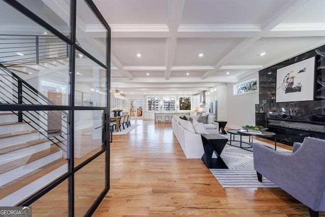 living room with coffered ceiling, ornamental molding, light hardwood / wood-style floors, and beamed ceiling