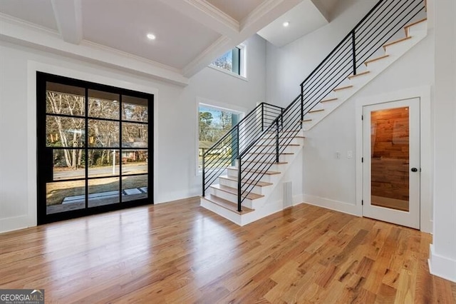 foyer entrance featuring beam ceiling, crown molding, and wood-type flooring