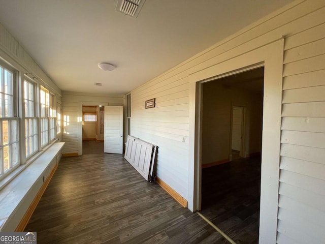 hall with dark wood-type flooring and wood walls