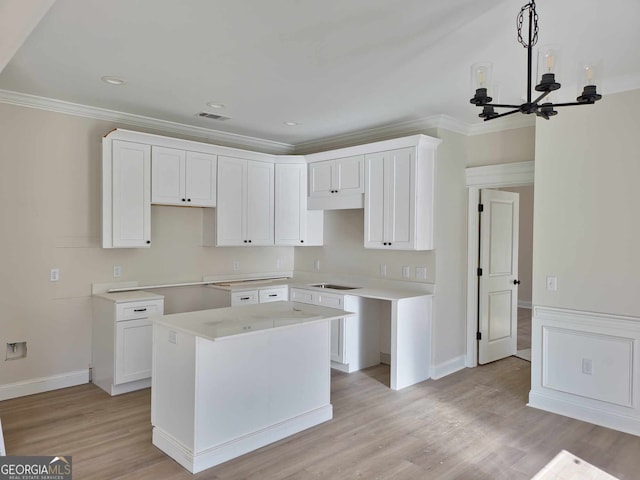 kitchen with light wood-type flooring, a center island, visible vents, and crown molding