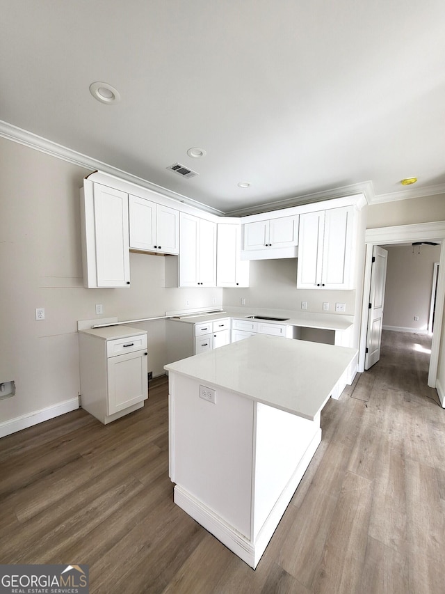 kitchen with visible vents, a kitchen island, wood finished floors, crown molding, and white cabinetry