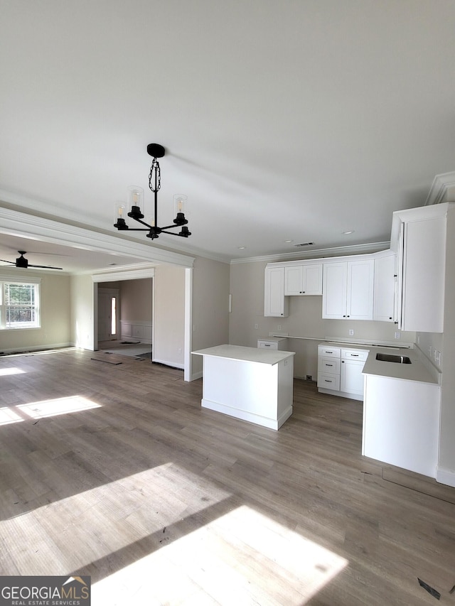 kitchen featuring a kitchen island, white cabinetry, open floor plan, and wood finished floors