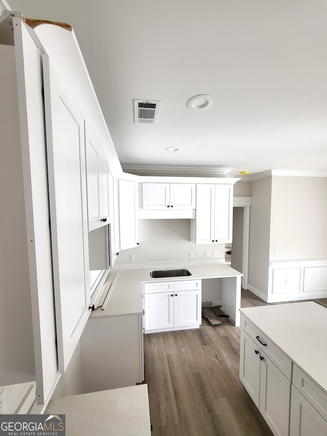 kitchen featuring a sink, white cabinetry, visible vents, and wood finished floors