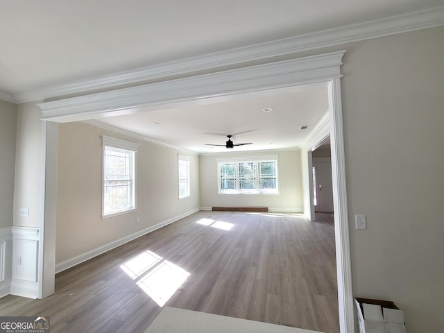 empty room with ornamental molding, wood finished floors, and a ceiling fan