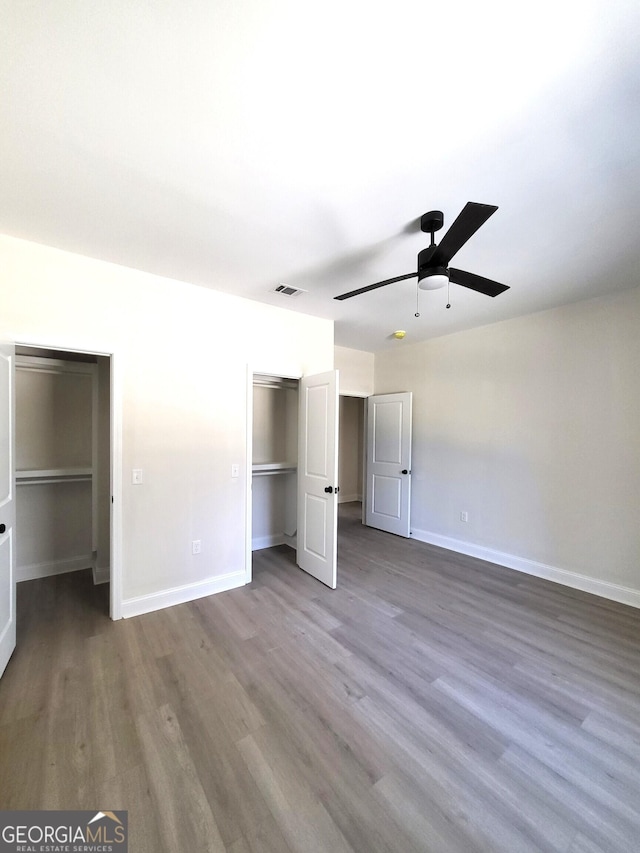 unfurnished bedroom featuring a closet, wood finished floors, visible vents, and baseboards