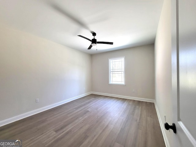 spare room featuring dark wood-style floors, a ceiling fan, and baseboards