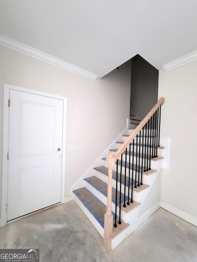 stairway featuring concrete flooring, baseboards, and crown molding