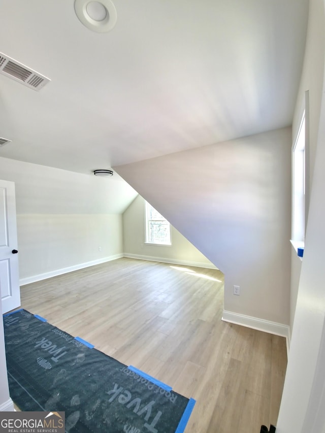 additional living space with lofted ceiling, baseboards, visible vents, and wood finished floors