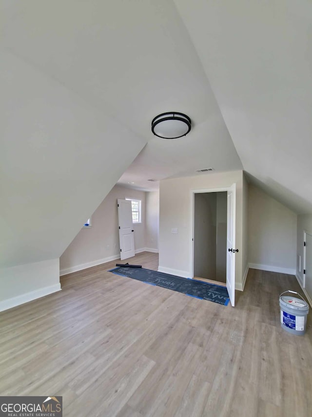 bonus room with baseboards, vaulted ceiling, and wood finished floors