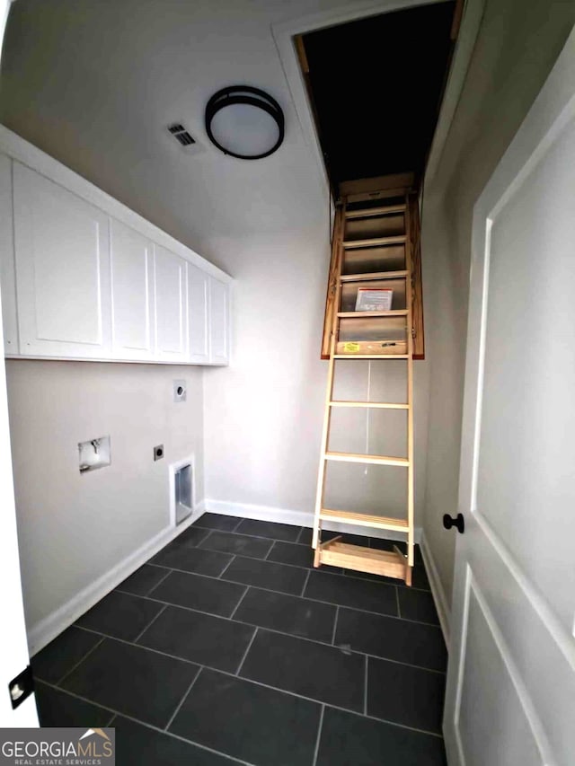 clothes washing area with cabinet space, baseboards, electric dryer hookup, and dark tile patterned flooring