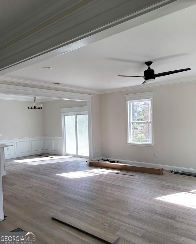 empty room featuring a healthy amount of sunlight, crown molding, and wood finished floors