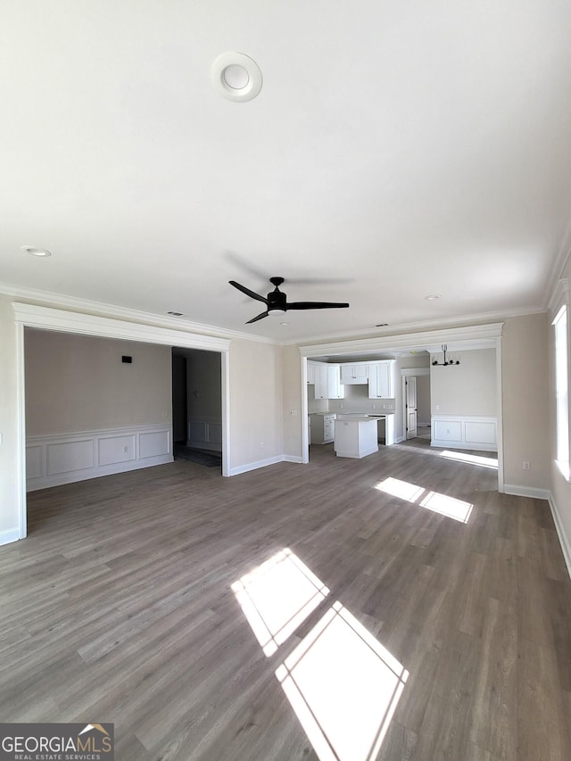 unfurnished living room featuring baseboards, wood finished floors, a ceiling fan, and crown molding