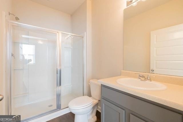 bathroom with toilet, a shower with shower door, and vanity