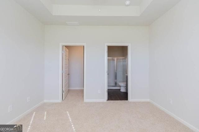 unfurnished bedroom featuring ensuite bath, a closet, a spacious closet, and light carpet