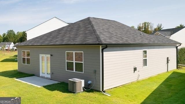 rear view of house featuring a lawn, central AC unit, and a patio