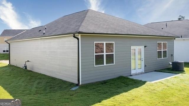 rear view of property with a patio area, central air condition unit, and a yard