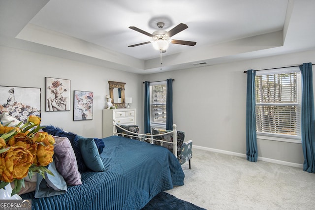 bedroom with carpet floors, ceiling fan, and a tray ceiling