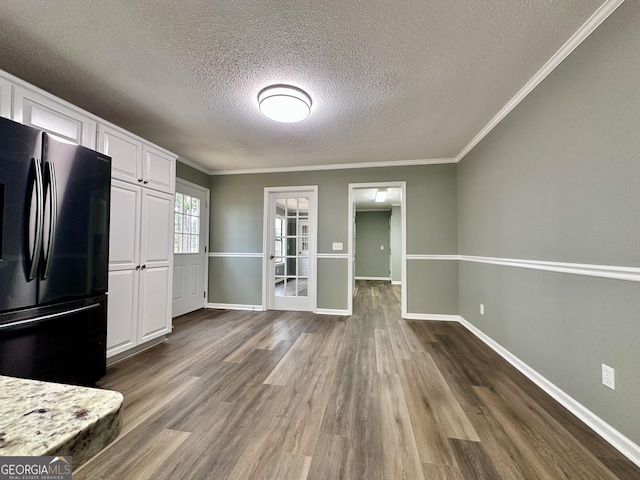 kitchen featuring light stone countertops, dark hardwood / wood-style floors, black fridge, white cabinets, and ornamental molding