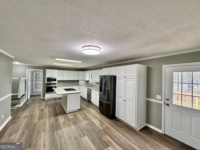 kitchen featuring stainless steel appliances, tasteful backsplash, crown molding, white cabinetry, and wood-type flooring