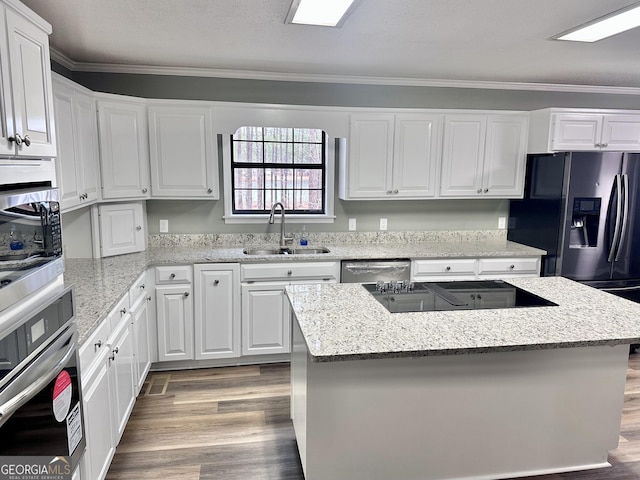 kitchen featuring sink, stainless steel appliances, white cabinetry, and a center island