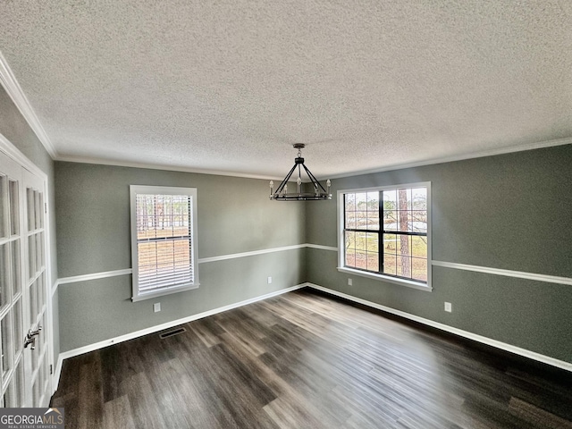 unfurnished dining area with an inviting chandelier, ornamental molding, a textured ceiling, and dark wood-type flooring