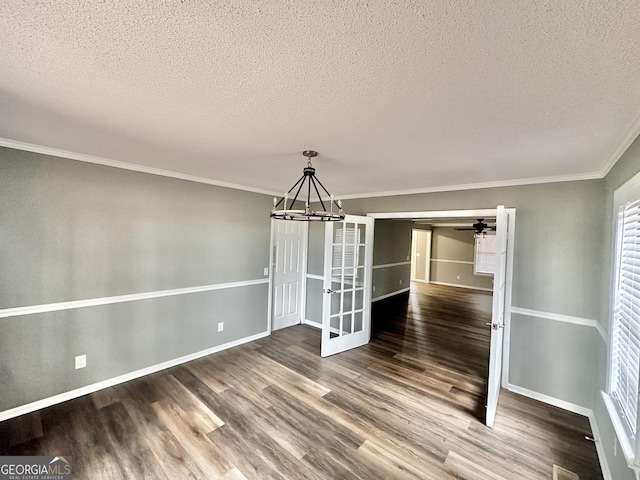 unfurnished dining area with a textured ceiling, an inviting chandelier, ornamental molding, and hardwood / wood-style flooring