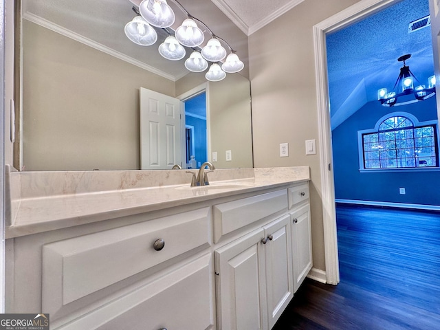 bathroom featuring a textured ceiling, lofted ceiling, hardwood / wood-style floors, ornamental molding, and vanity